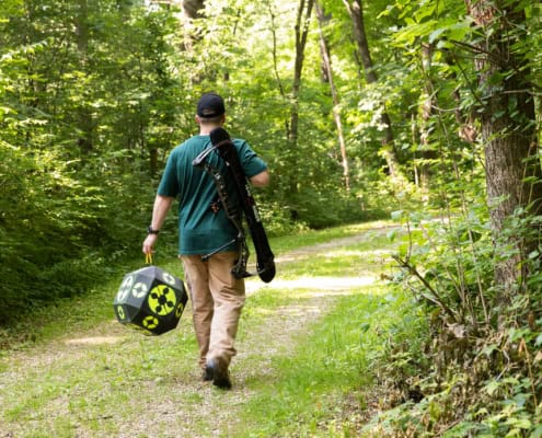Man walks away from camera carrying a target and a Dead Ringer EZ Bow Sling